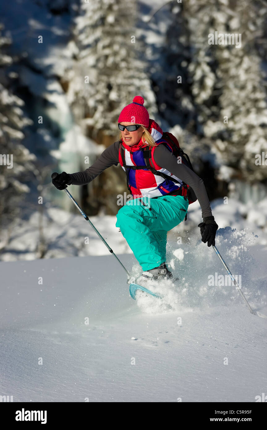 Eine Frau läuft durch tiefen Pulver Schnee in Schneeschuhen. Stockfoto