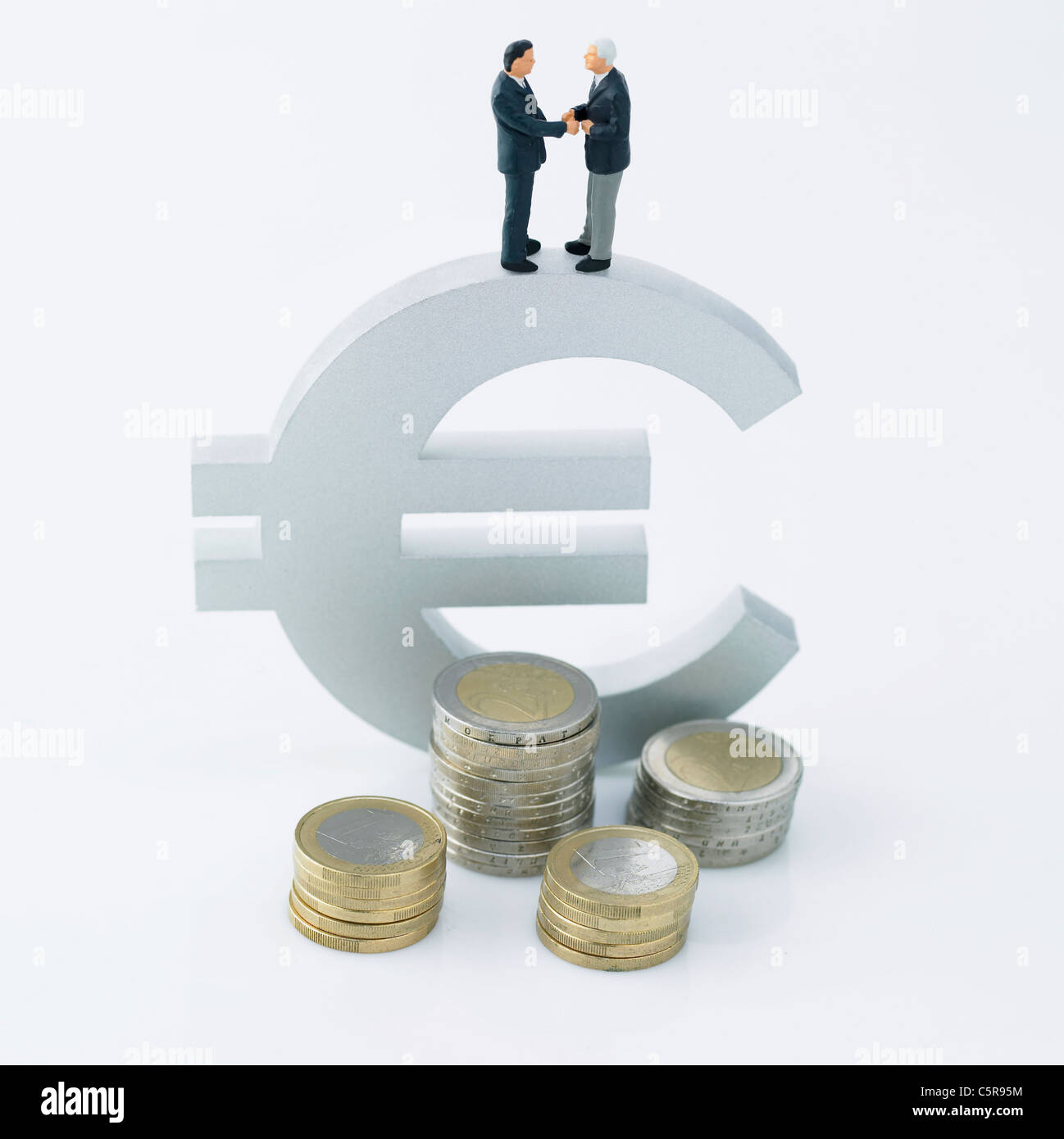 Zwei Figuren Händeschütteln auf ein Währungszeichen Stockfoto