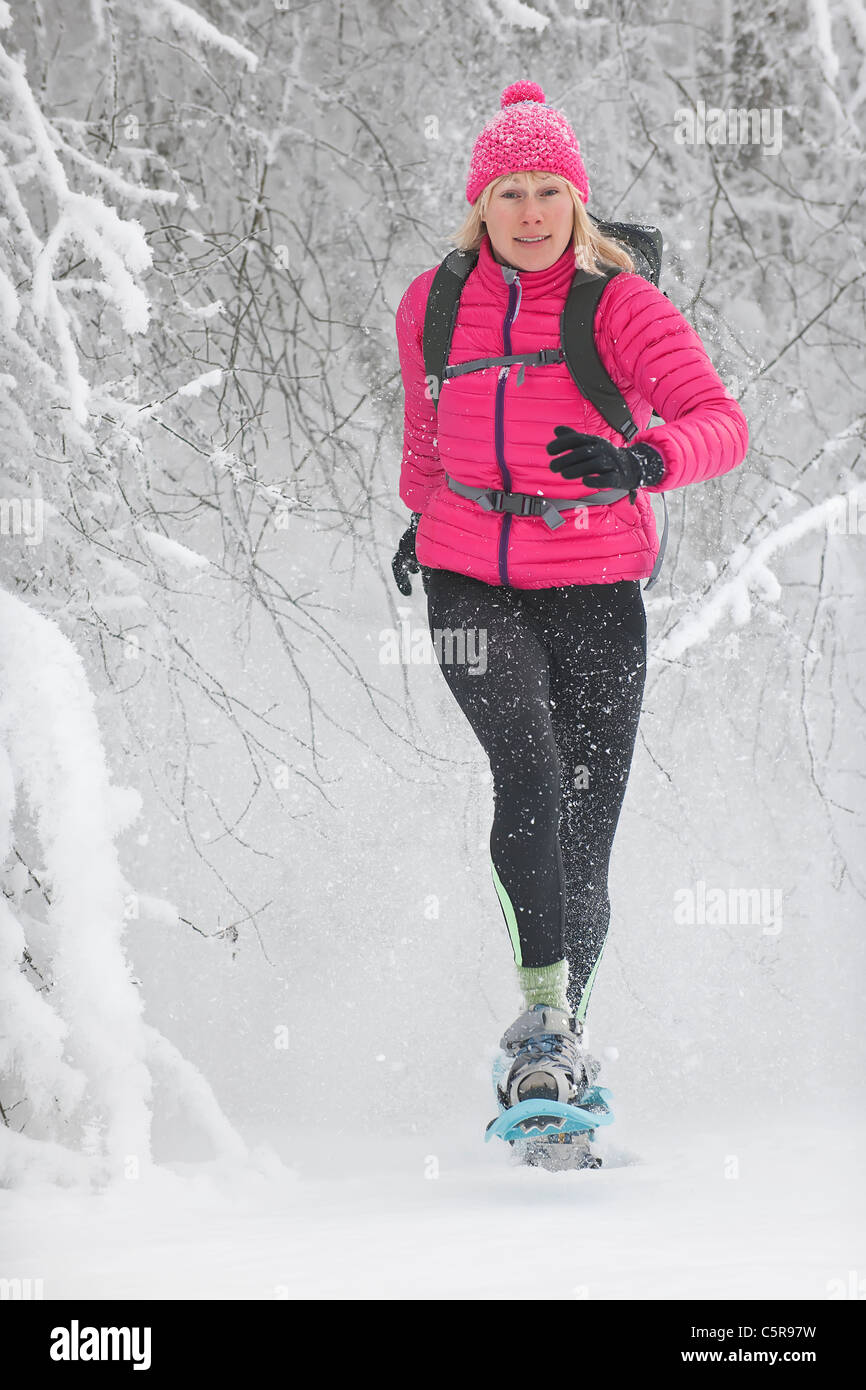 Eine Frau, Schneeschuhwandern durch verschneite Bäume platzt. Stockfoto