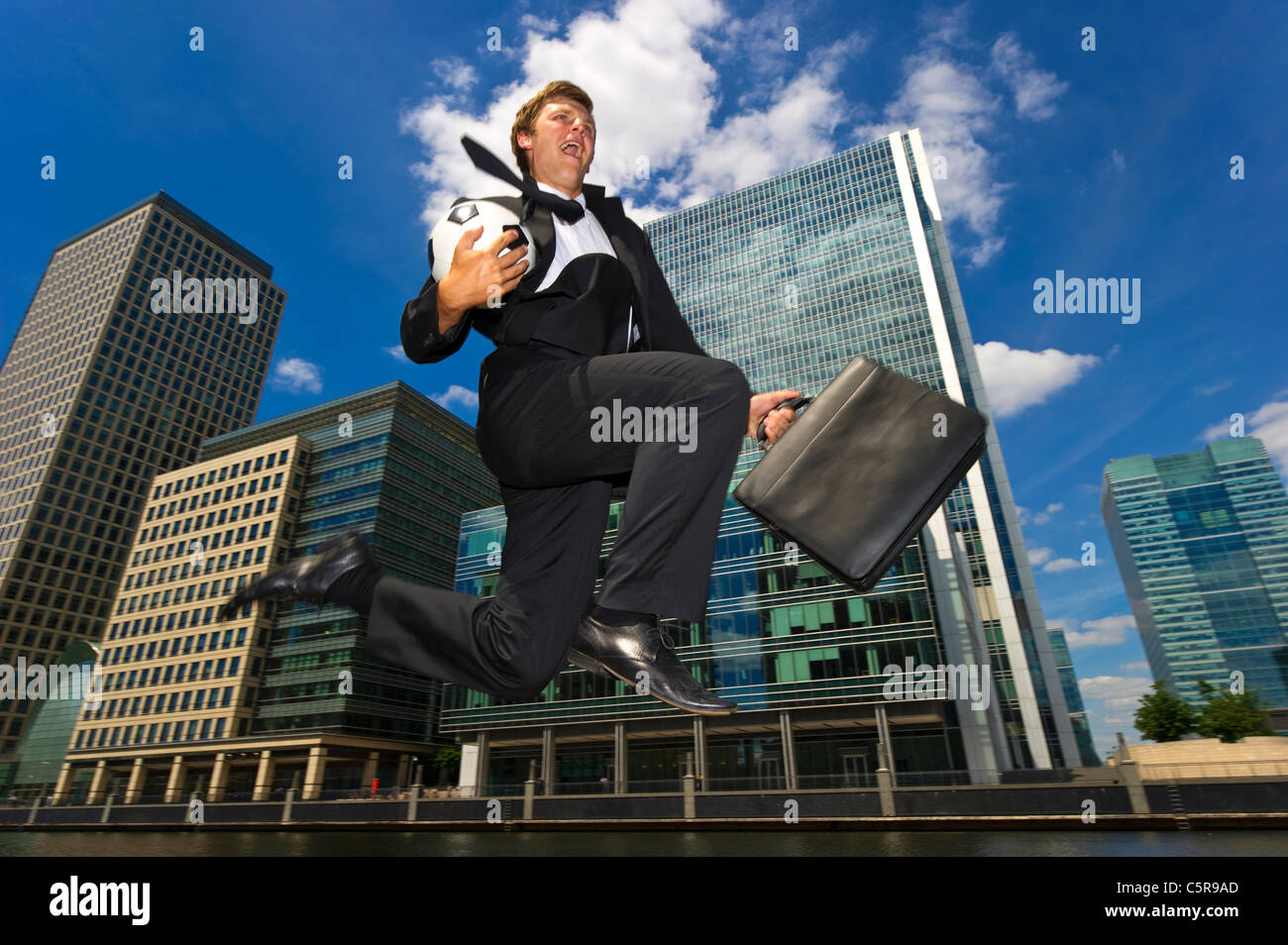 Eine glückliche Fußball spielen Geschäftsmann das Büro verlassen zu müssen. Stockfoto