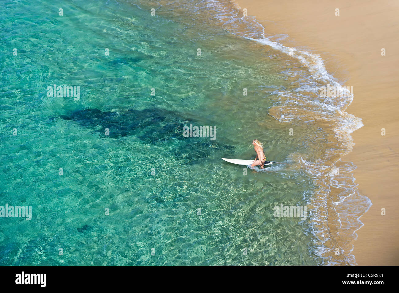 Ein junge blonde Surfer geht ins Meer. Stockfoto