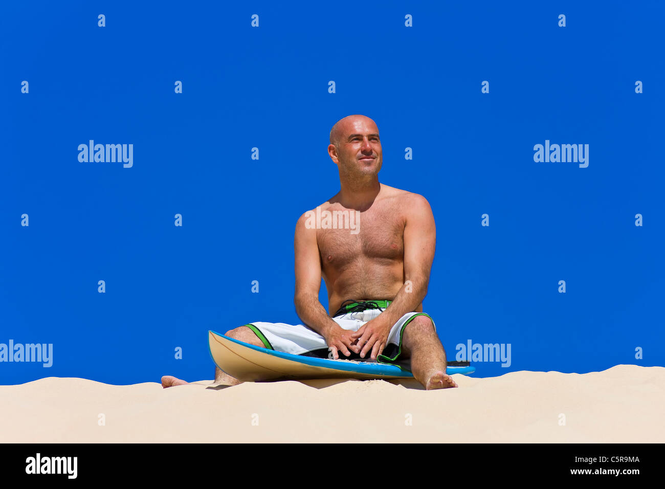 Surfer Lächeln an Bord sitzen am Strand. Stockfoto