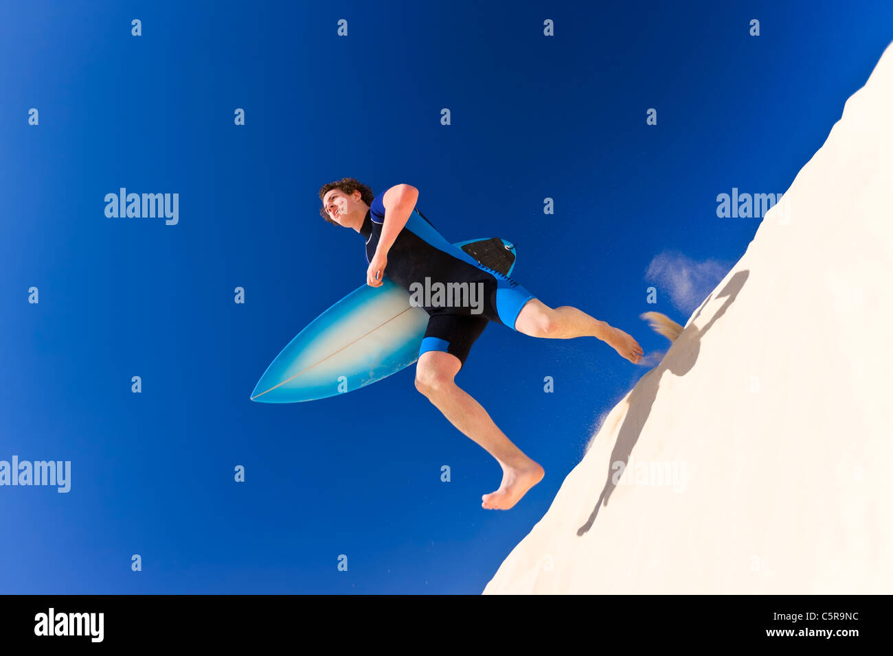 Surfer über Sanddünen bis zum Meer laufen. Stockfoto