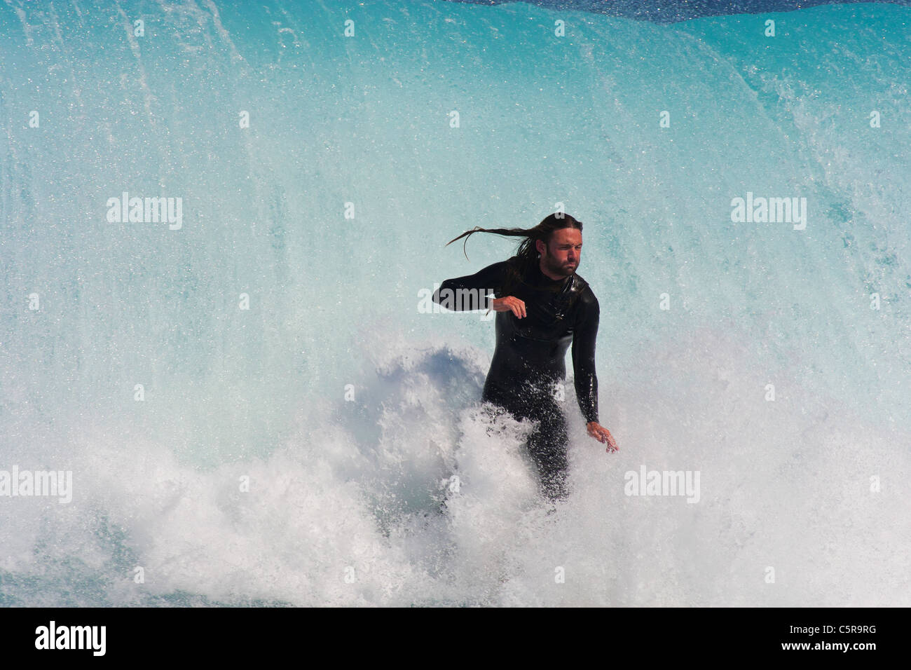 Diese Surfer nimmt einen tiefen Atemzug, wie er durch die massive Welle hinter ihm herausgenommen werden soll. Stockfoto