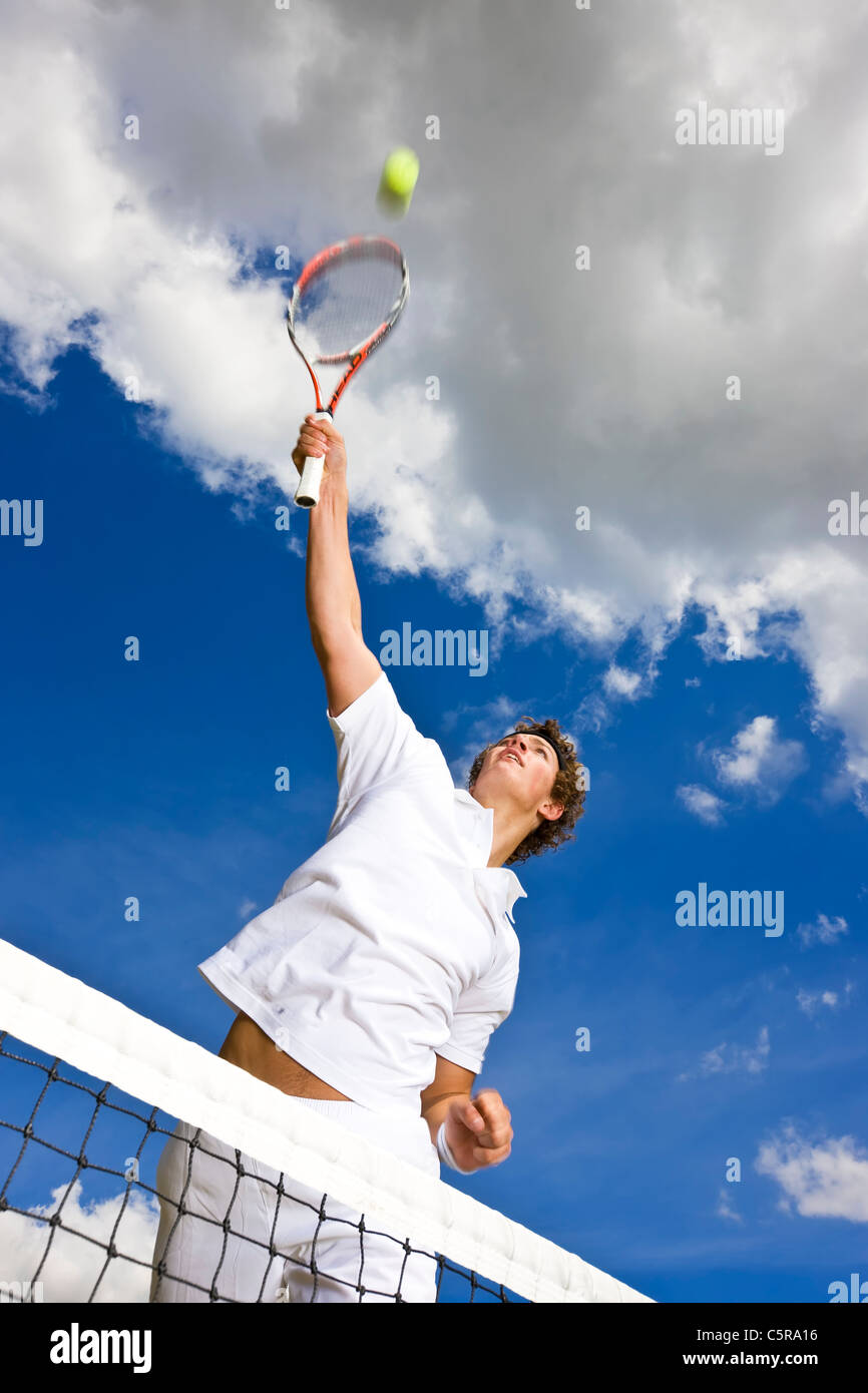 Ein Tennisspieler erstreckt sich hoch über das Netz, Ball für Sollwert zu zerschlagen. Stockfoto