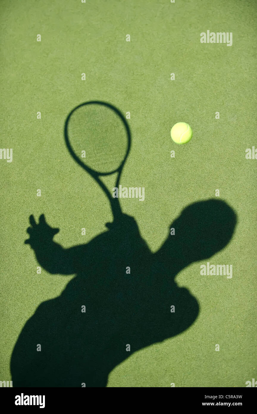 Eine Tennis-Spieler-Silhouette gibt den Ball zurück. Stockfoto