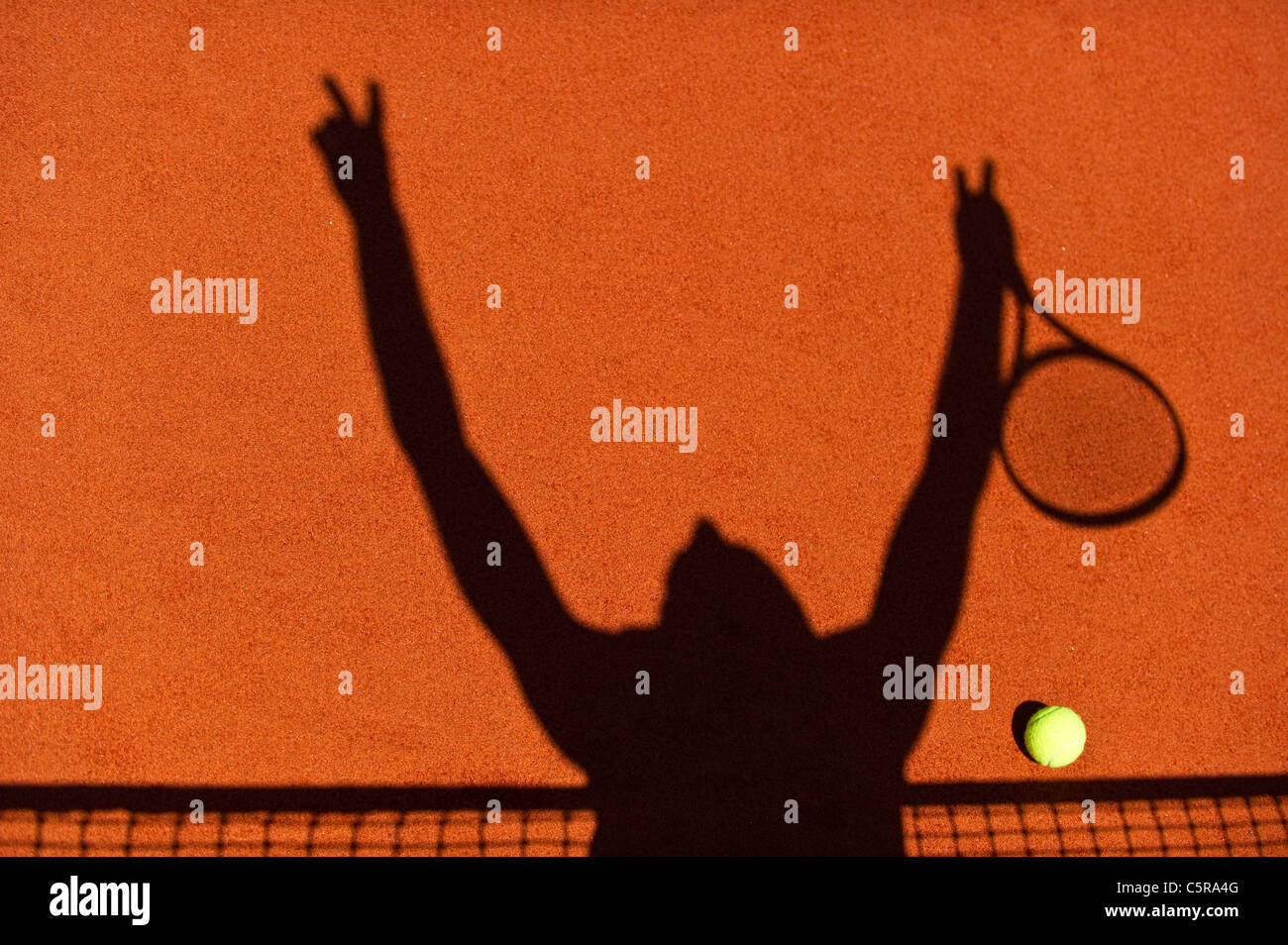 Die Silhouette eines Tennisspielers feiert am Netz. Stockfoto