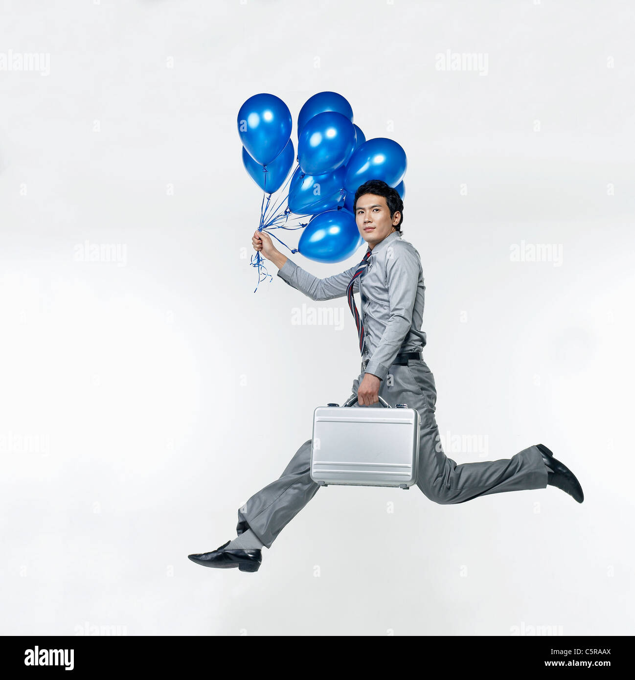 Ein Mann, der blaue Ballons und eine Aktentasche Stockfoto
