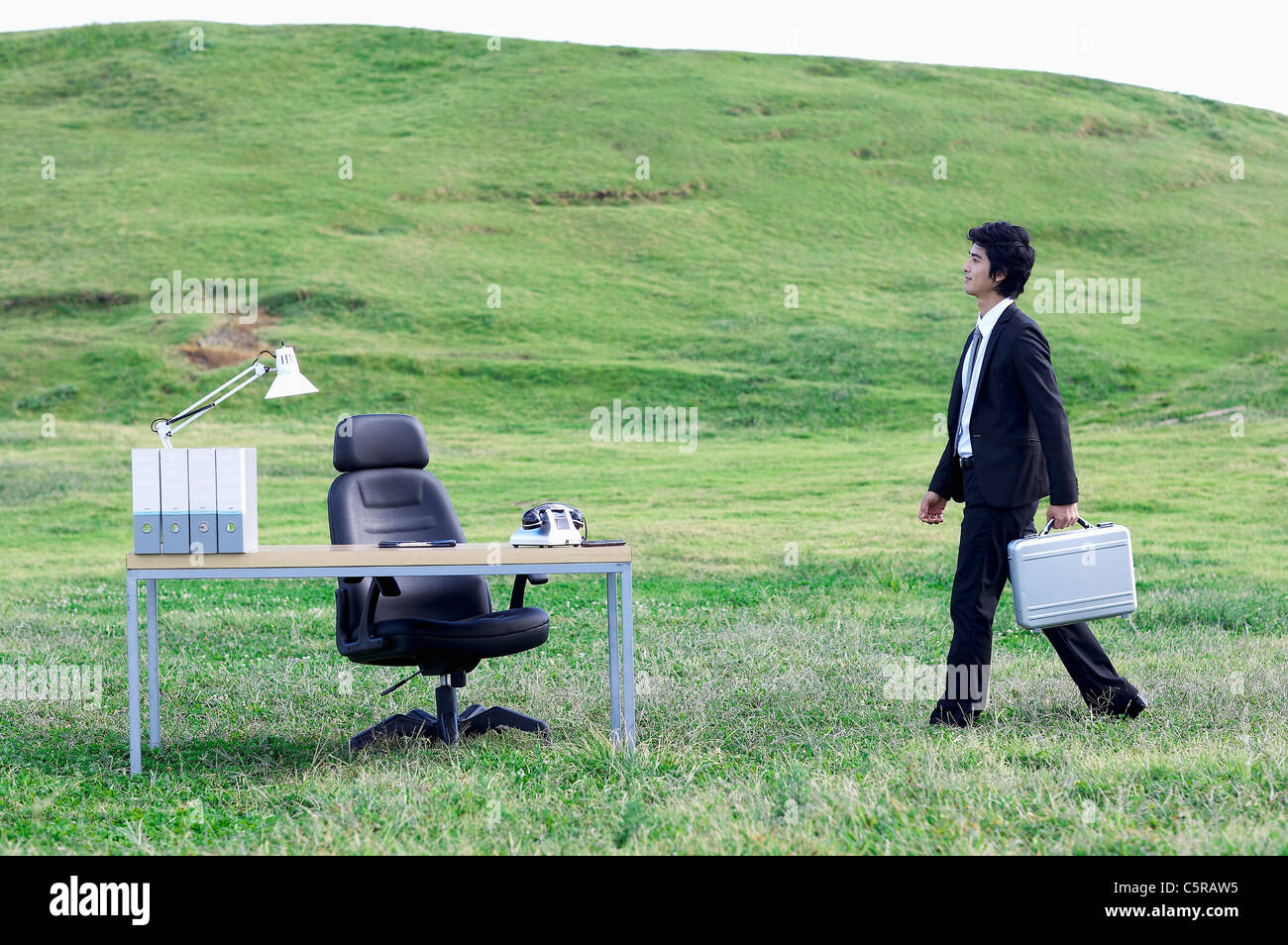 Ein Mann geht zu seinem Schreibtisch auf dem Rasen Stockfoto