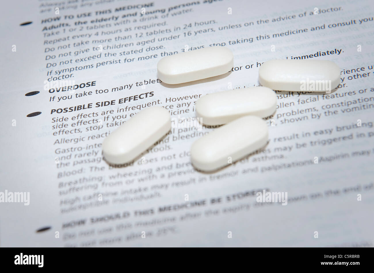 Weiße Pillen auf wichtige Informationen über mögliche Nebenwirkungen und Überdosierung Stockfoto