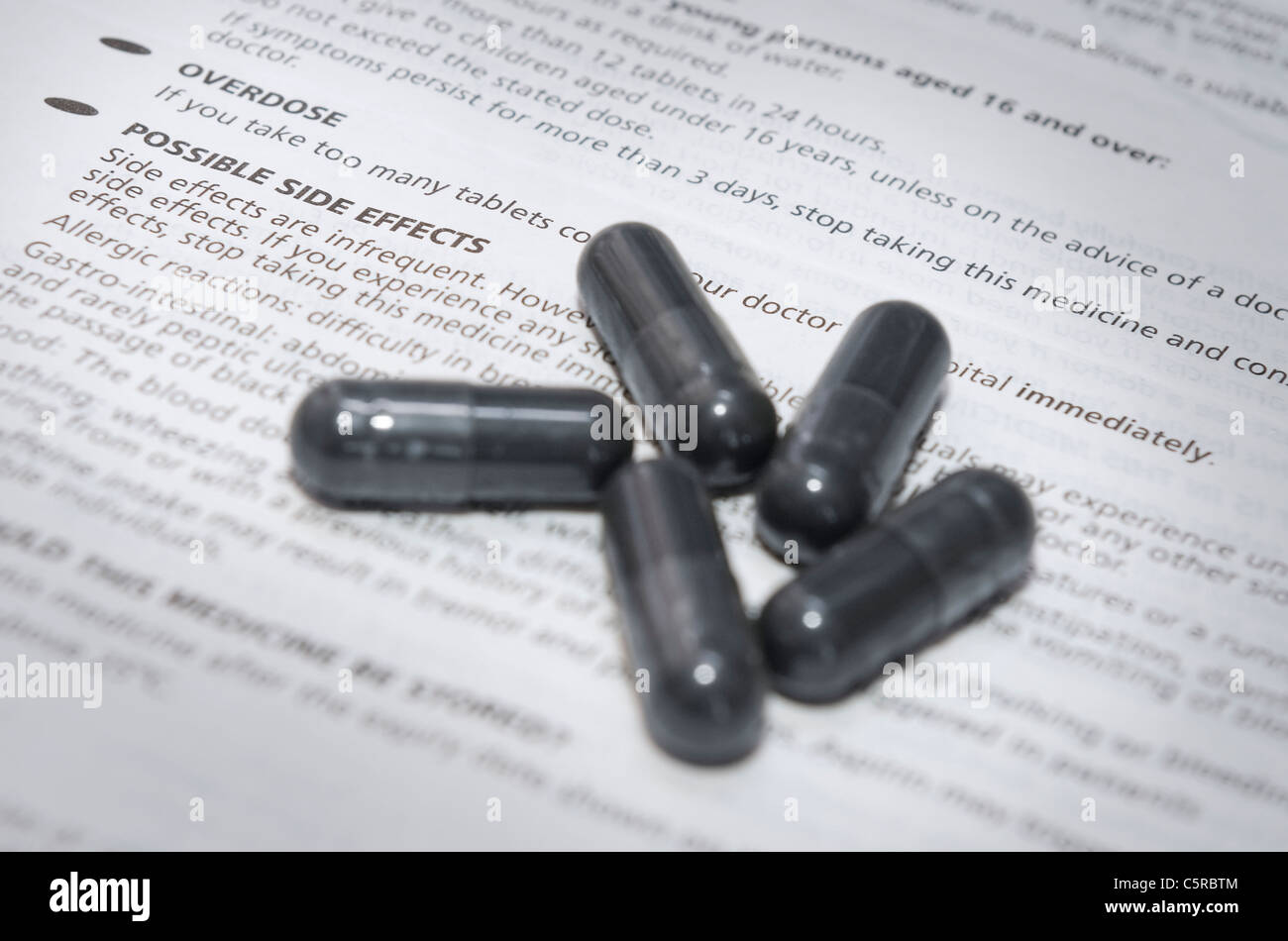 Schwarze Kapsel Pillen auf wichtige Informationen über mögliche Nebenwirkungen und Überdosis Stockfoto