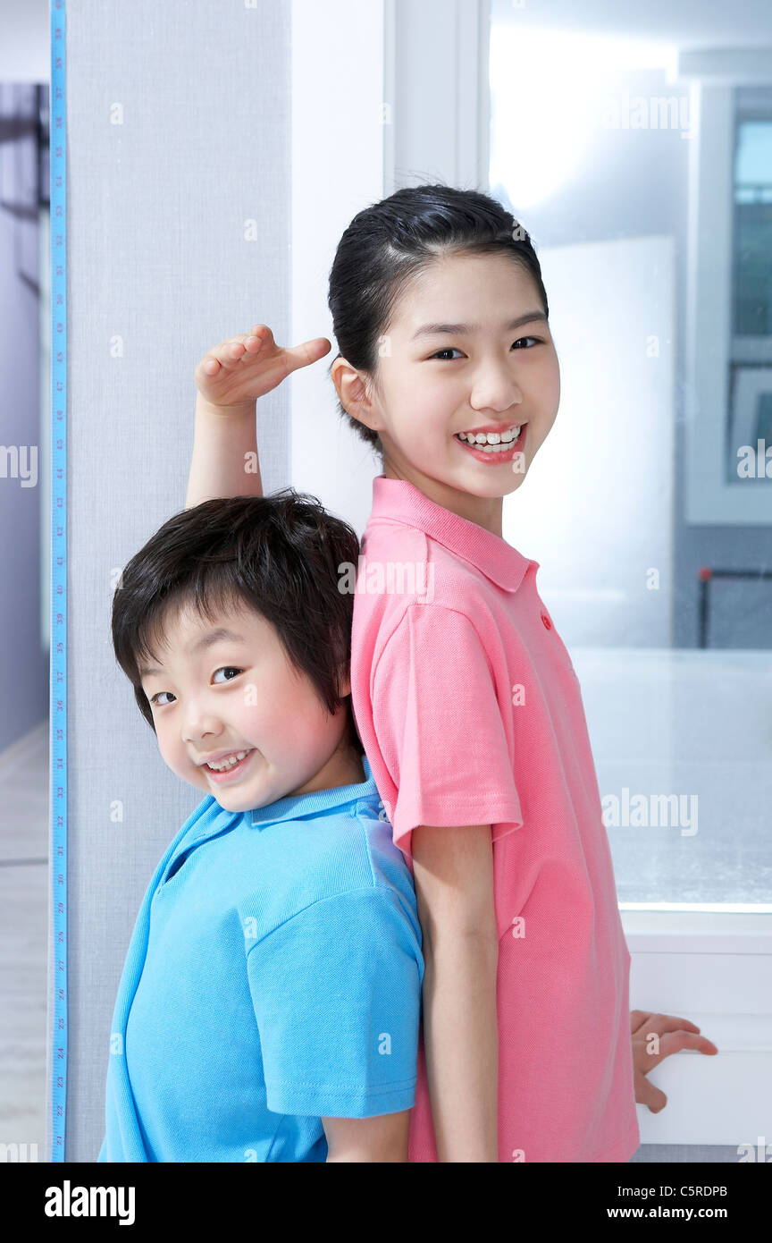 Ein Junge und ein Mädchen ihre Höhe zu messen Stockfoto
