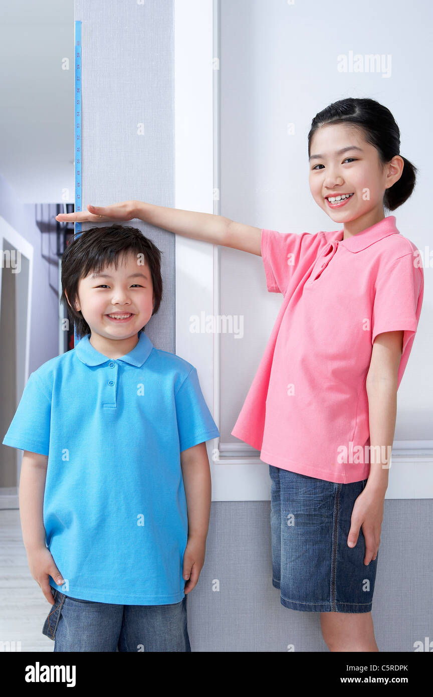 Ein Junge und ein Mädchen ihre Höhe zu messen Stockfoto