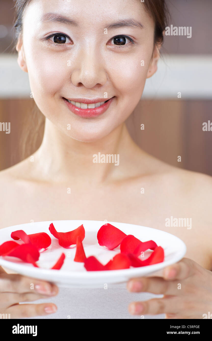 Verlässt eine Frau halten Schale voll mit roten Blumen Stockfoto