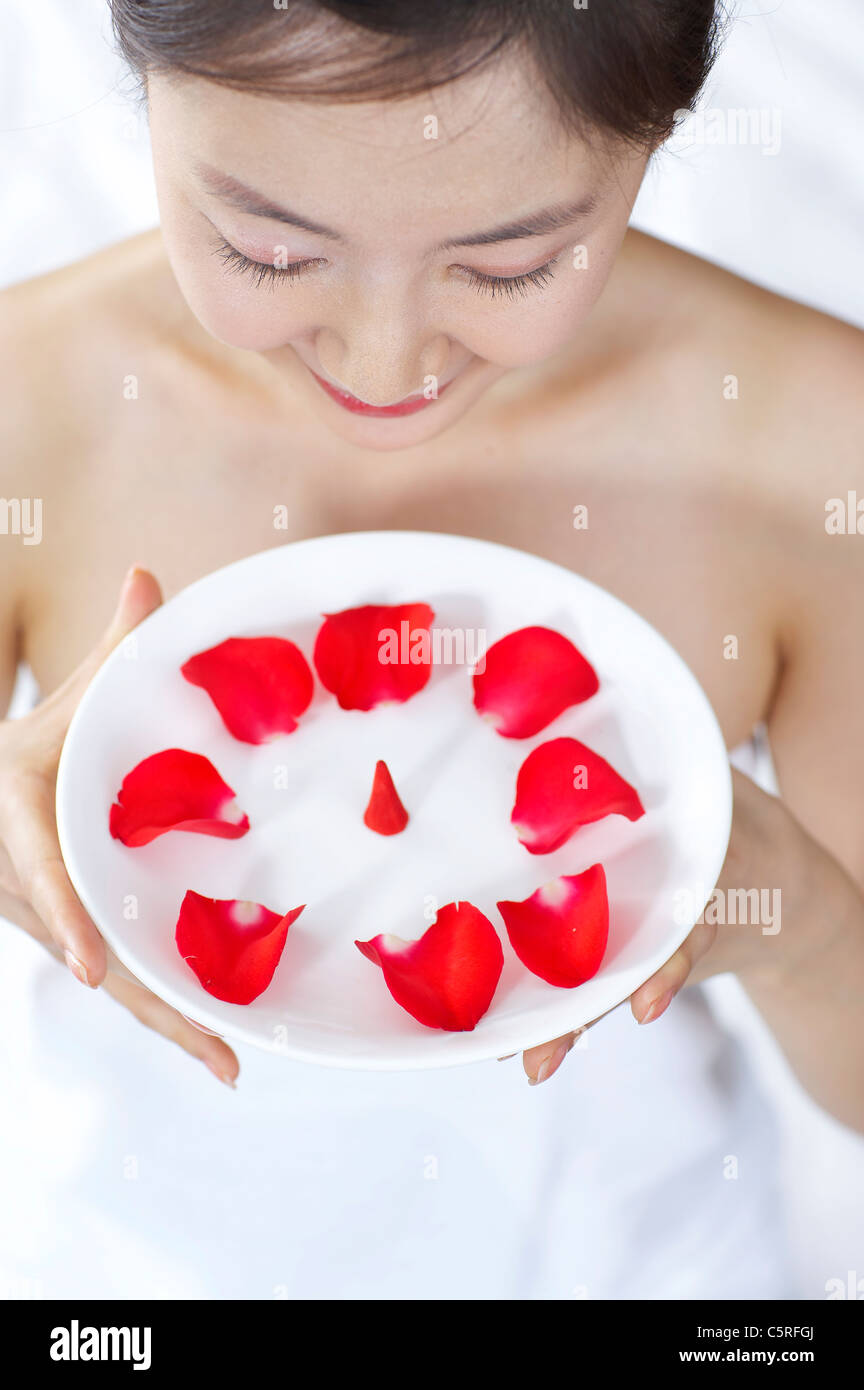 Verlässt eine Frau halten Schale voll mit roten Blumen Stockfoto