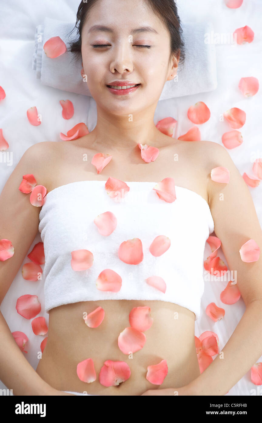 Eine Frau in Massagetisch bedeckt mit Blüten Stockfoto