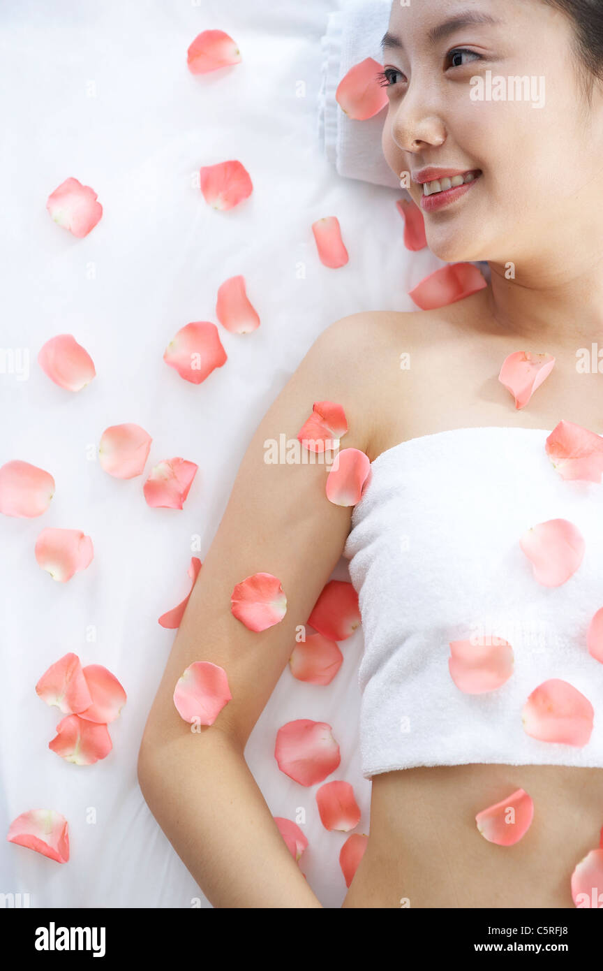 Eine Frau in Massagetisch bedeckt mit Blüten Stockfoto