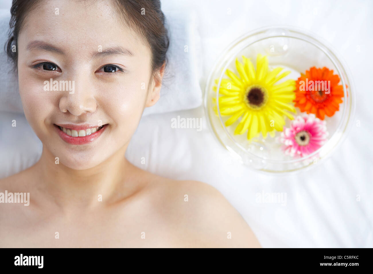 Eine Frau mit Blumen in die Wasserschale liegend Stockfoto