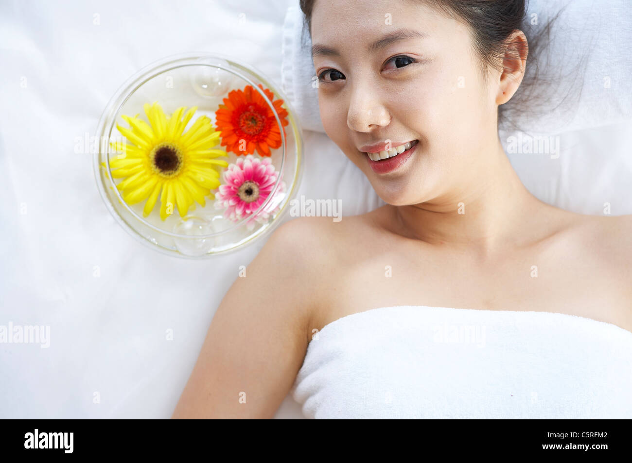 Eine Frau mit Blumen in die Wasserschale liegend Stockfoto