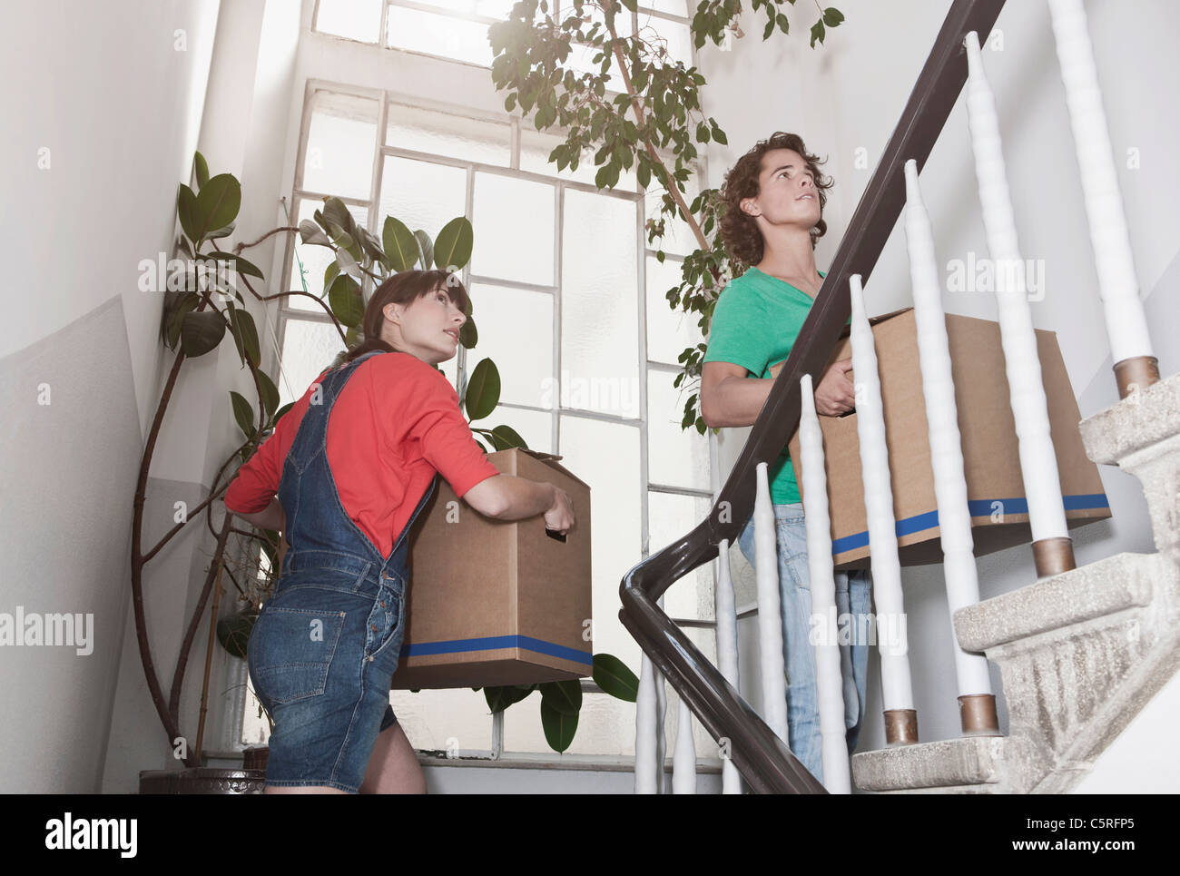 Deutschland, Köln, junge Paar Tragetasche Karton auf Treppe in die Renovierung der Wohnung Stockfoto