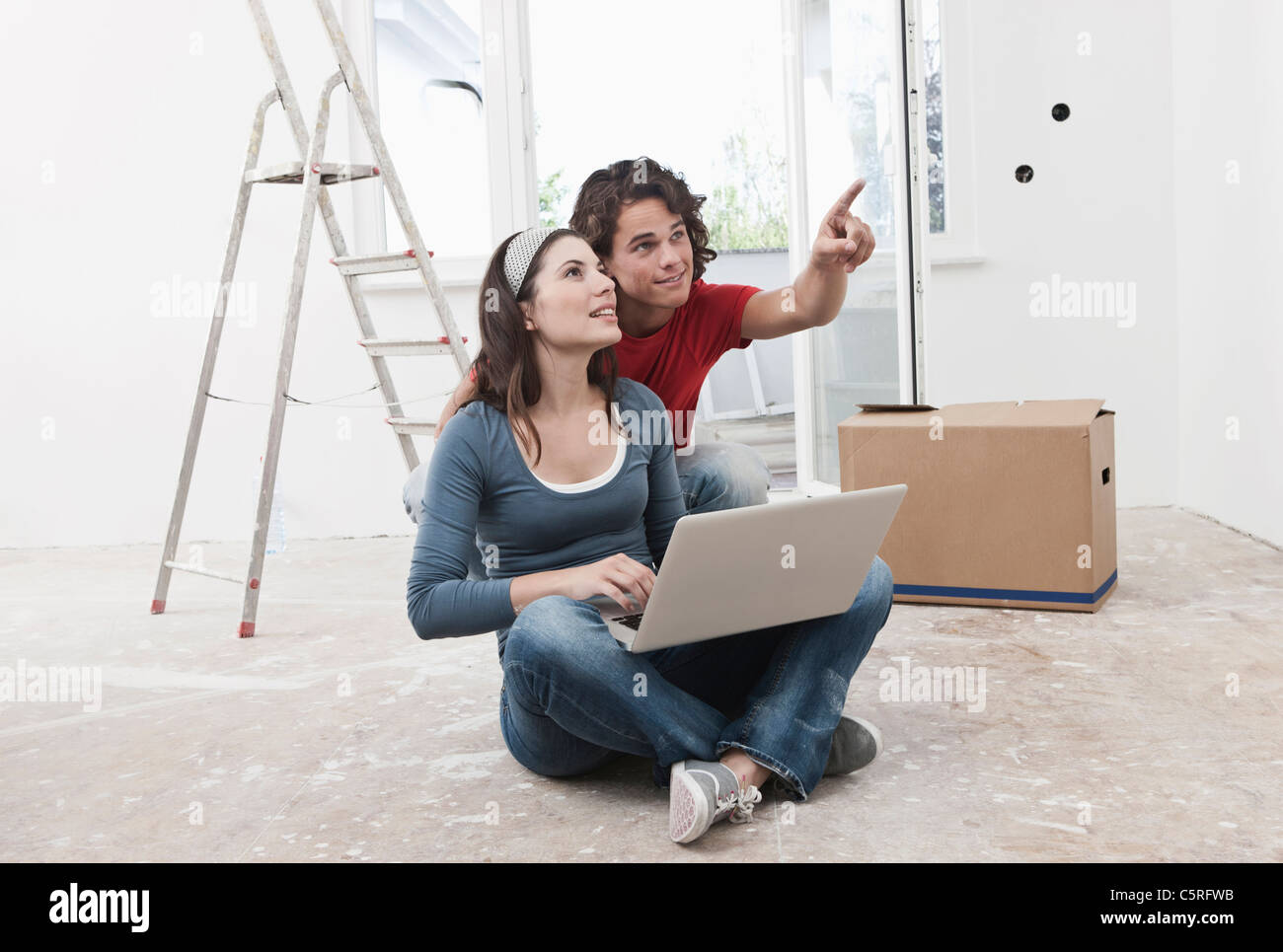 Deutschland, Köln, junges Paar mit Laptop und zeigt bei der Renovierung der Wohnung Stockfoto