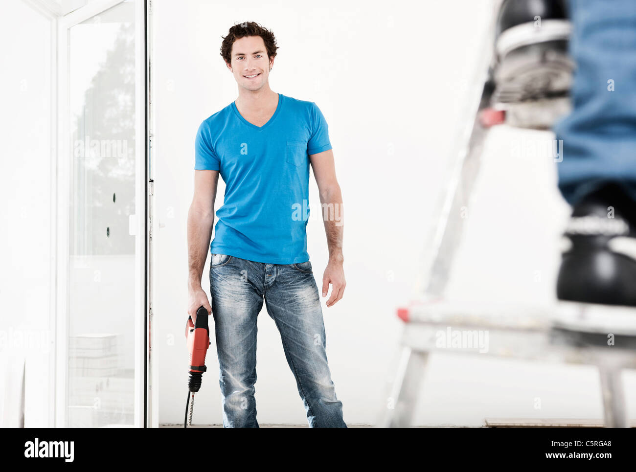 Deutschland, Köln, junger Mann mit elektrischen Bohrer in die Renovierung der Wohnung Stockfoto