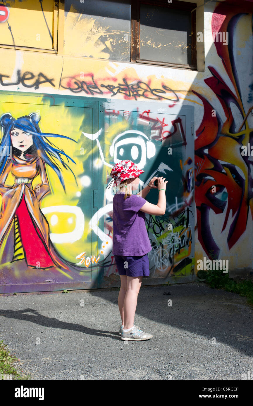 Ein junges Mädchen steht Fotografieren eines Gebäudes mit künstlerischen Graffiti in Chamonix Mont Blanc, Frankreich bedeckt. Stockfoto