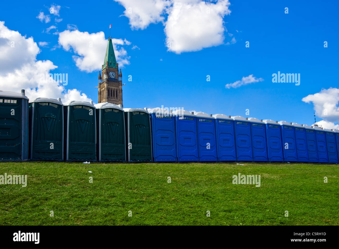 Eine lange Reihe von mobilen Toiletten mit dem kanadischen Peace Tower des Parlaments im Hintergrund. Stockfoto