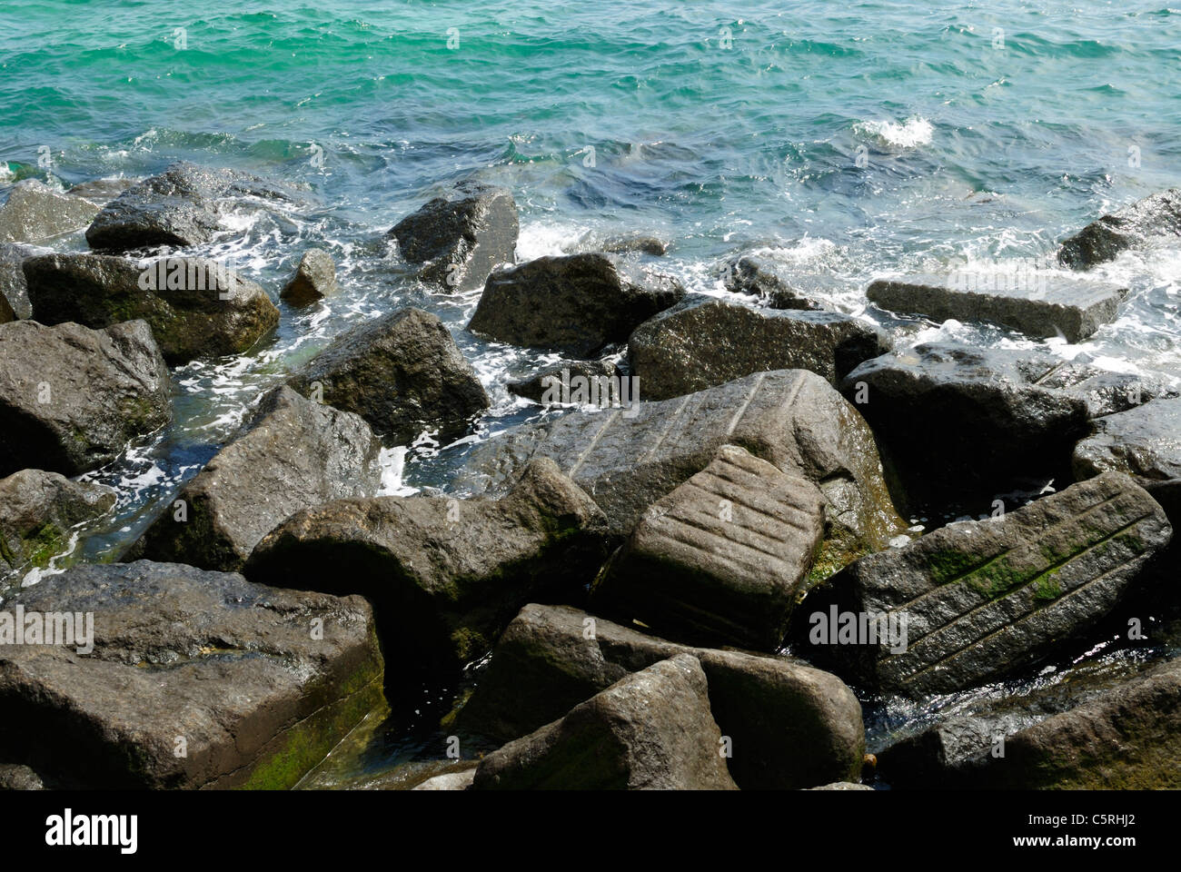 Meerwasser spritzt gegen Felsen und Geröll Stockfoto