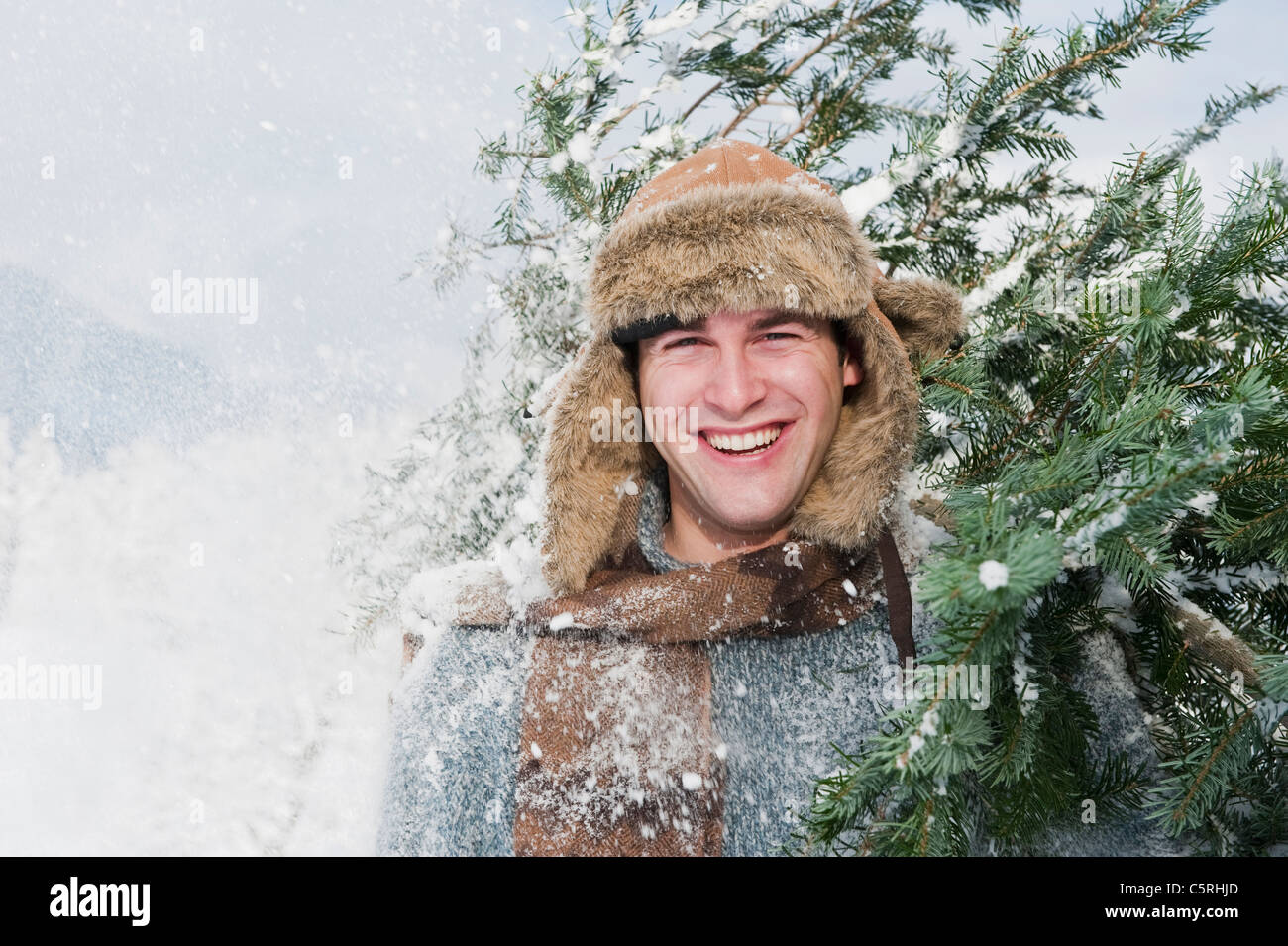 Österreich, Salzburger Land, Flachau, junger Mann mit Weihnachtsbaum im Schnee Stockfoto