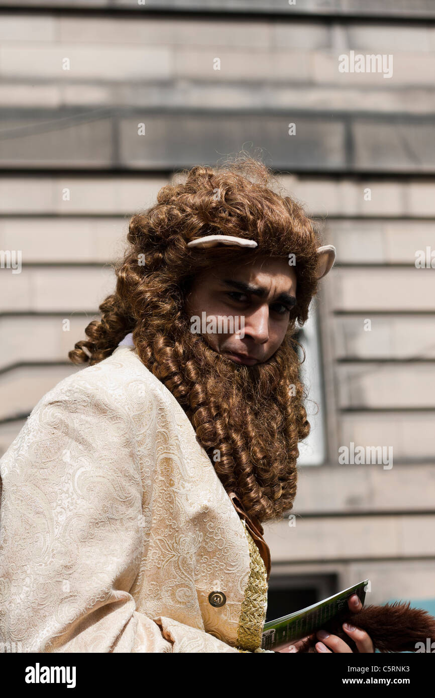 Ein Mann gekleidet wie der Löwe von Wizard of Oz, Flieger auf Edinburghs Royal Mile, Hände Förderung seiner Show am Rande Stockfoto