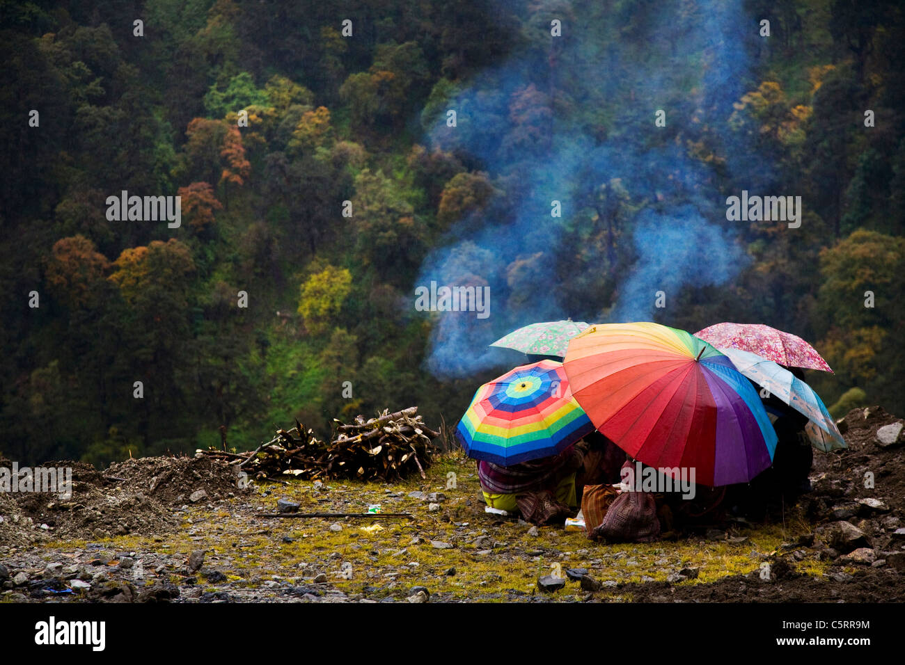 Straßenarbeiter Zuflucht unter ihren Sonnenschirmen wie es nieselt. Tawang, Arunachal Pradesh. Indien Stockfoto