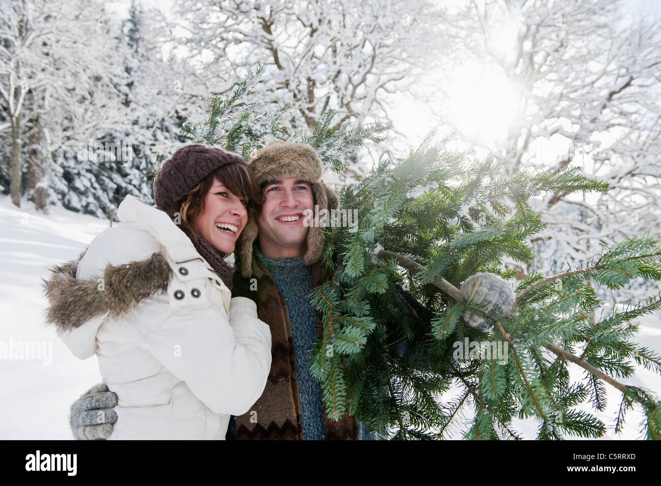 Österreich, Salzburger Land, Flachau, junger Mann und Frau mit Weihnachtsbaum im Schnee Stockfoto