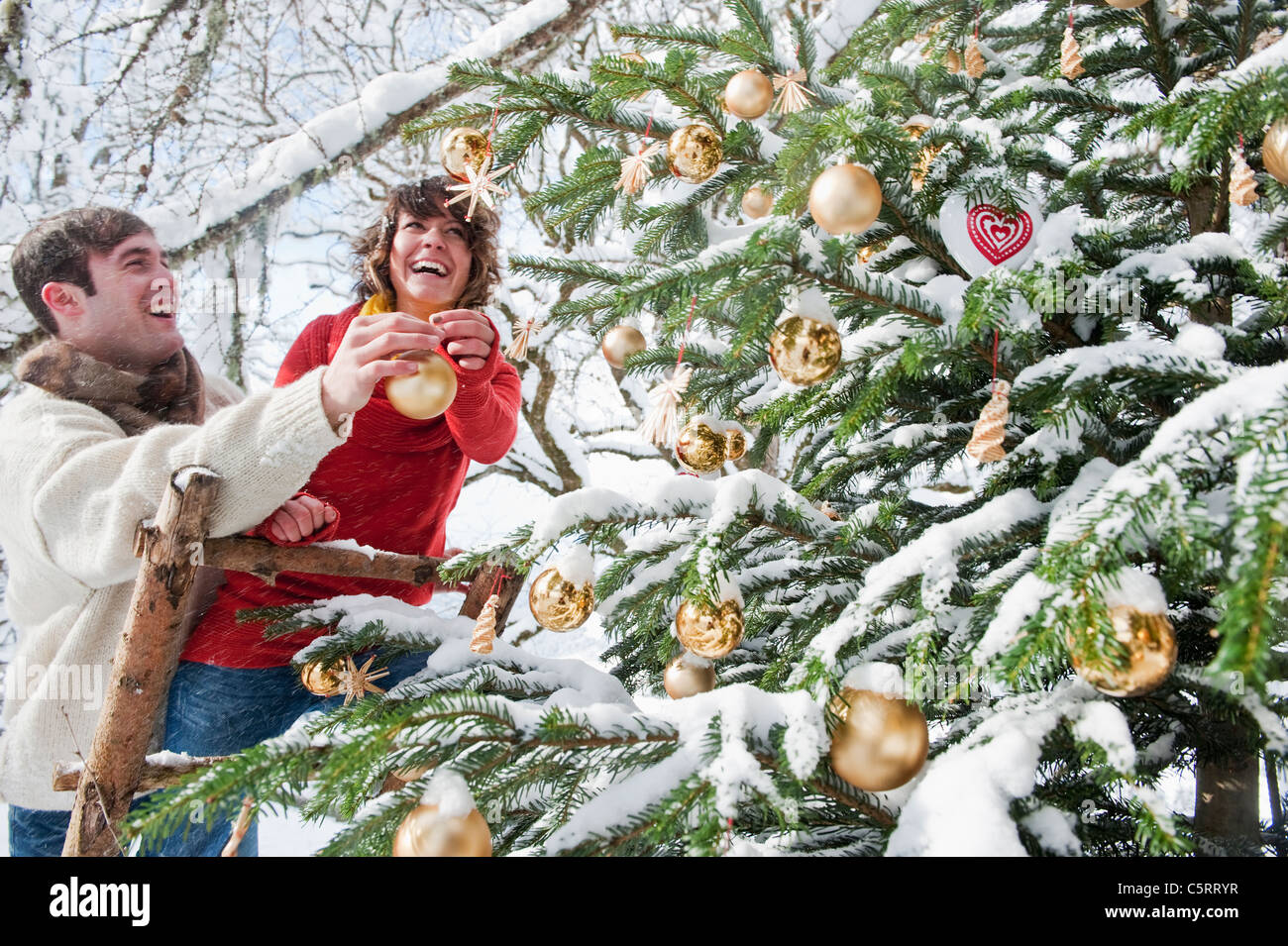 Österreich, Salzburger Land, Flachau, junger Mann und Frau schmücken Weihnachtsbaum im winter Stockfoto