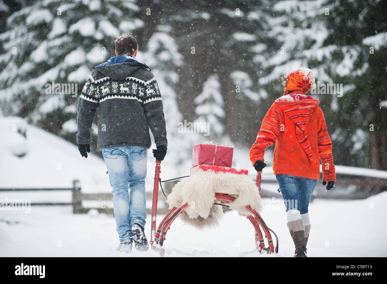 Österreich, Salzburger Land, Flachau, junger Mann und Frau, die Weihnachten Pakete auf Schlitten im Schnee Stockfoto