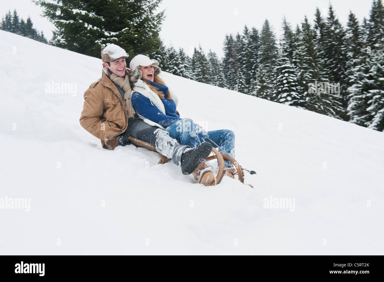 Junger Mann und Frau Rodeln im Schnee, Flachau, Salzburger Land, Österreich Stockfoto