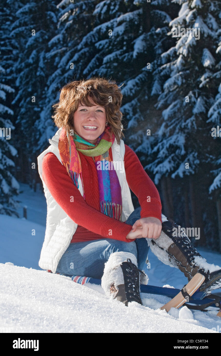 Österreich, Salzburger Land, Flachau, junge Frau sitzt auf Schlitten im Schnee Stockfoto