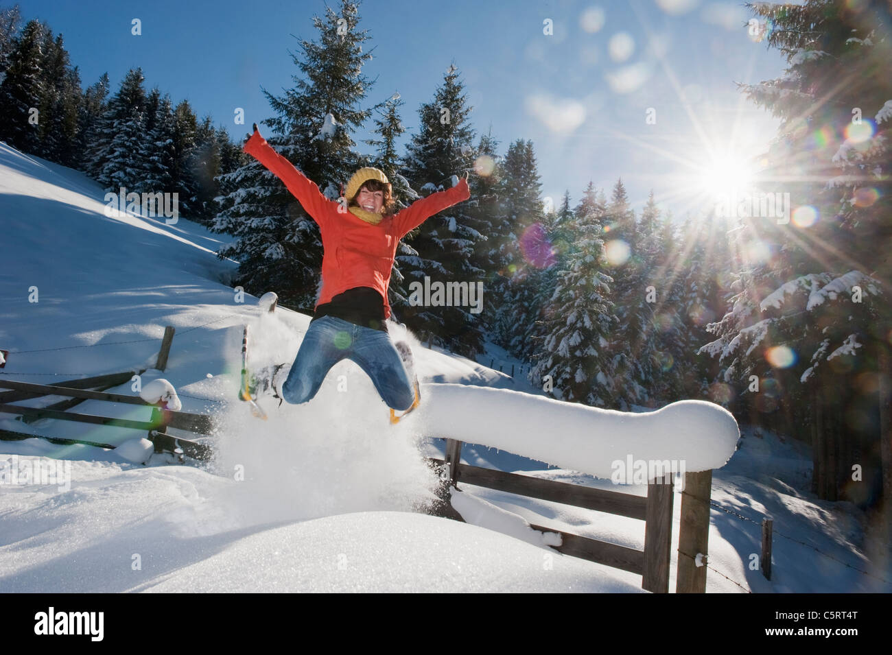 Österreich, Salzburger Land, Flachau, junge Frau mit Schneeschuhen springen im Schnee Stockfoto