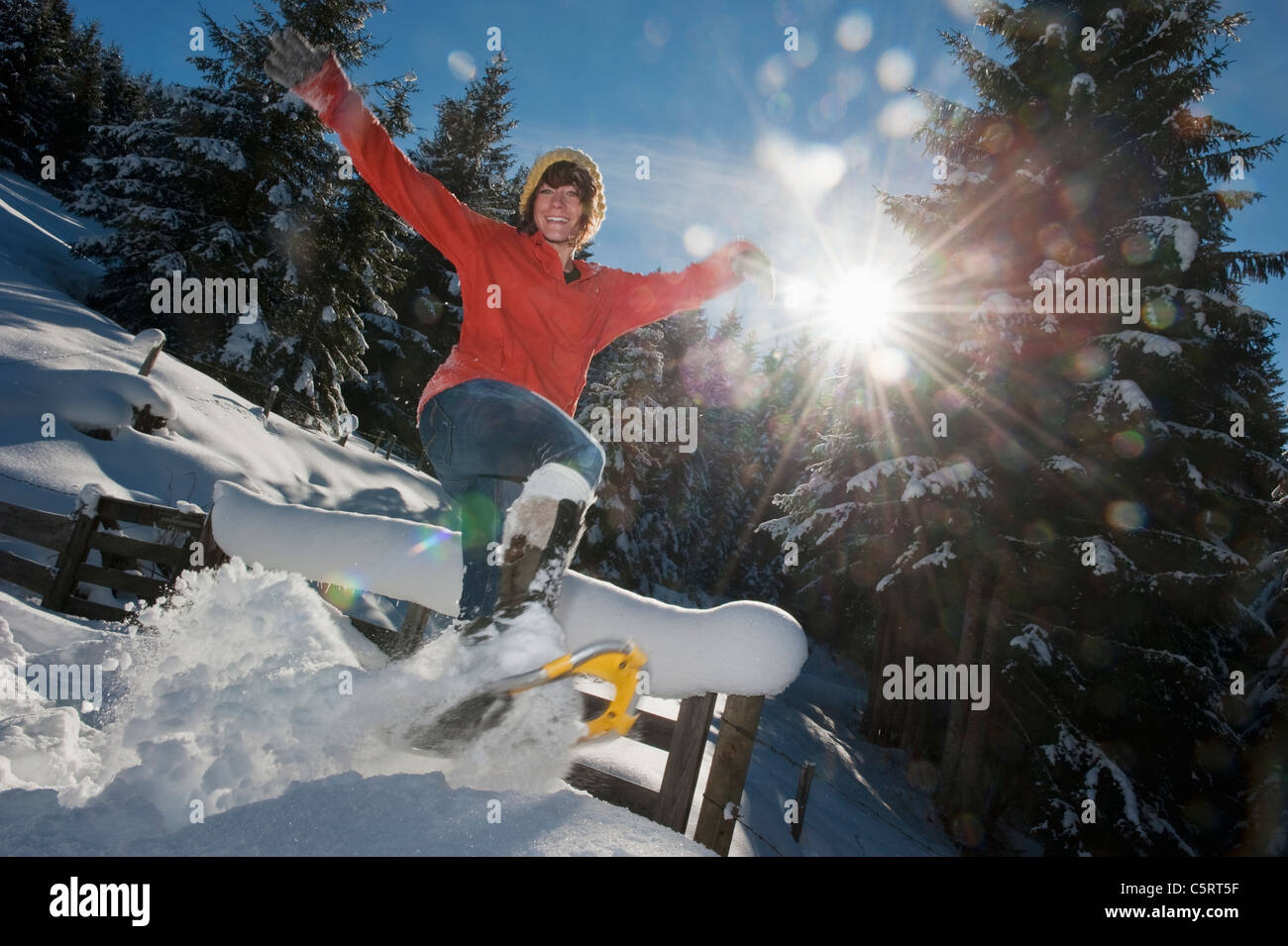 Österreich, Salzburger Land, Flachau, junge Frau mit Schneeschuhen springen im Schnee Stockfoto