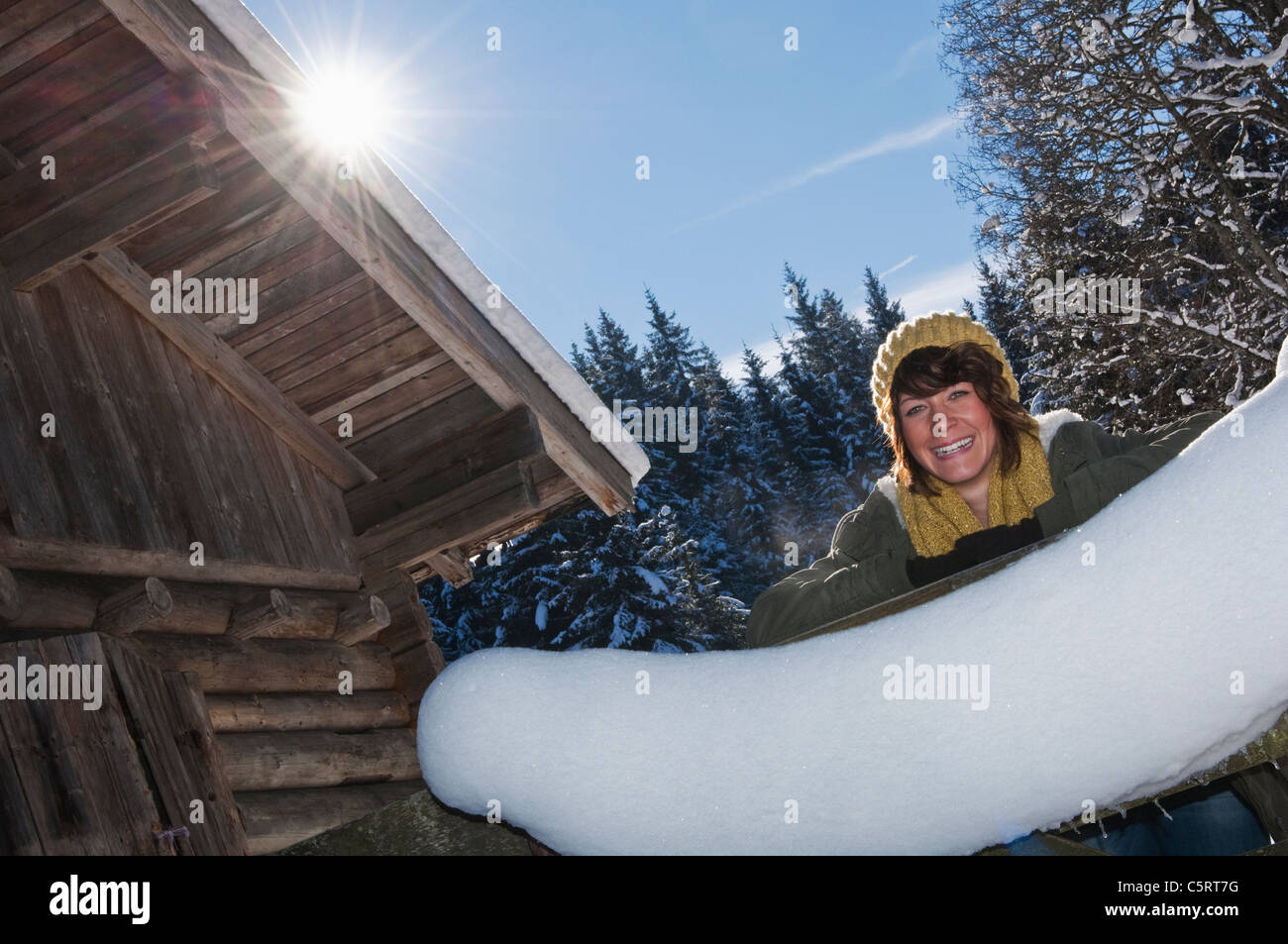 Österreich, Salzburger Land, Flachau, junge Frau, stützte sich auf hölzernen Zaun im Schnee Stockfoto