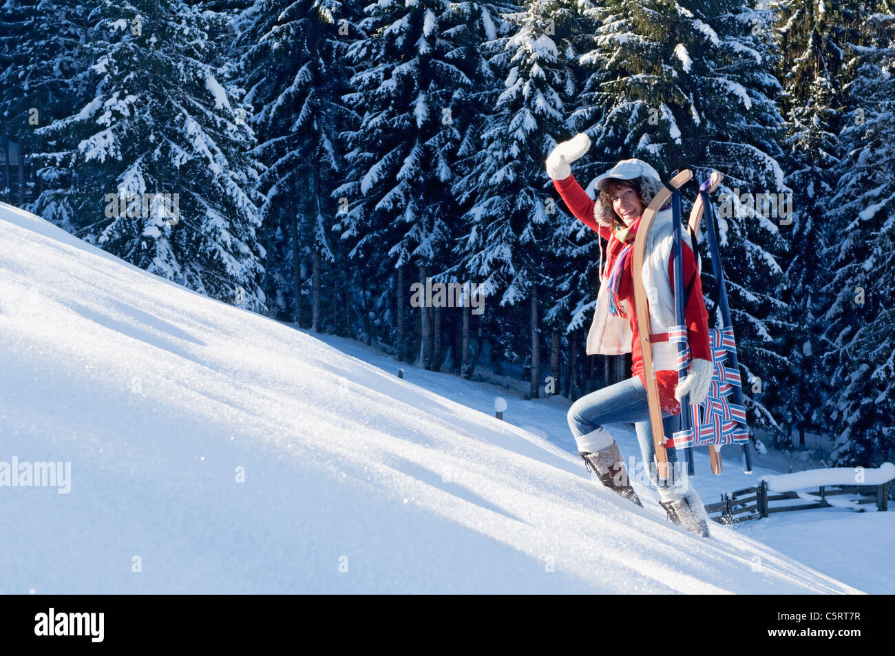 Österreich, Salzburger Land, Flachau, junge Frau, die zu Fuß mit Schlitten im Schnee Stockfoto