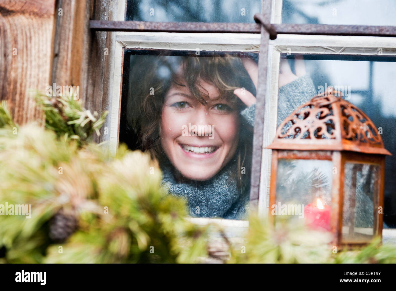Österreich, Salzburger Land, Flachau, junge Frau, die durch Fenster im winter Stockfoto