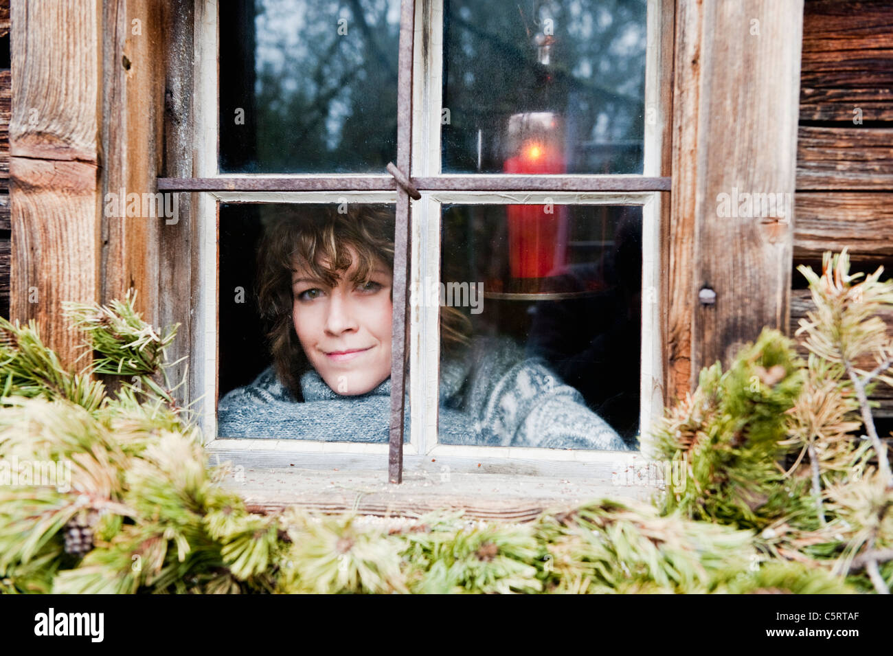Österreich, Salzburger Land, Flachau, junge Frau, die durch Fenster im winter Stockfoto