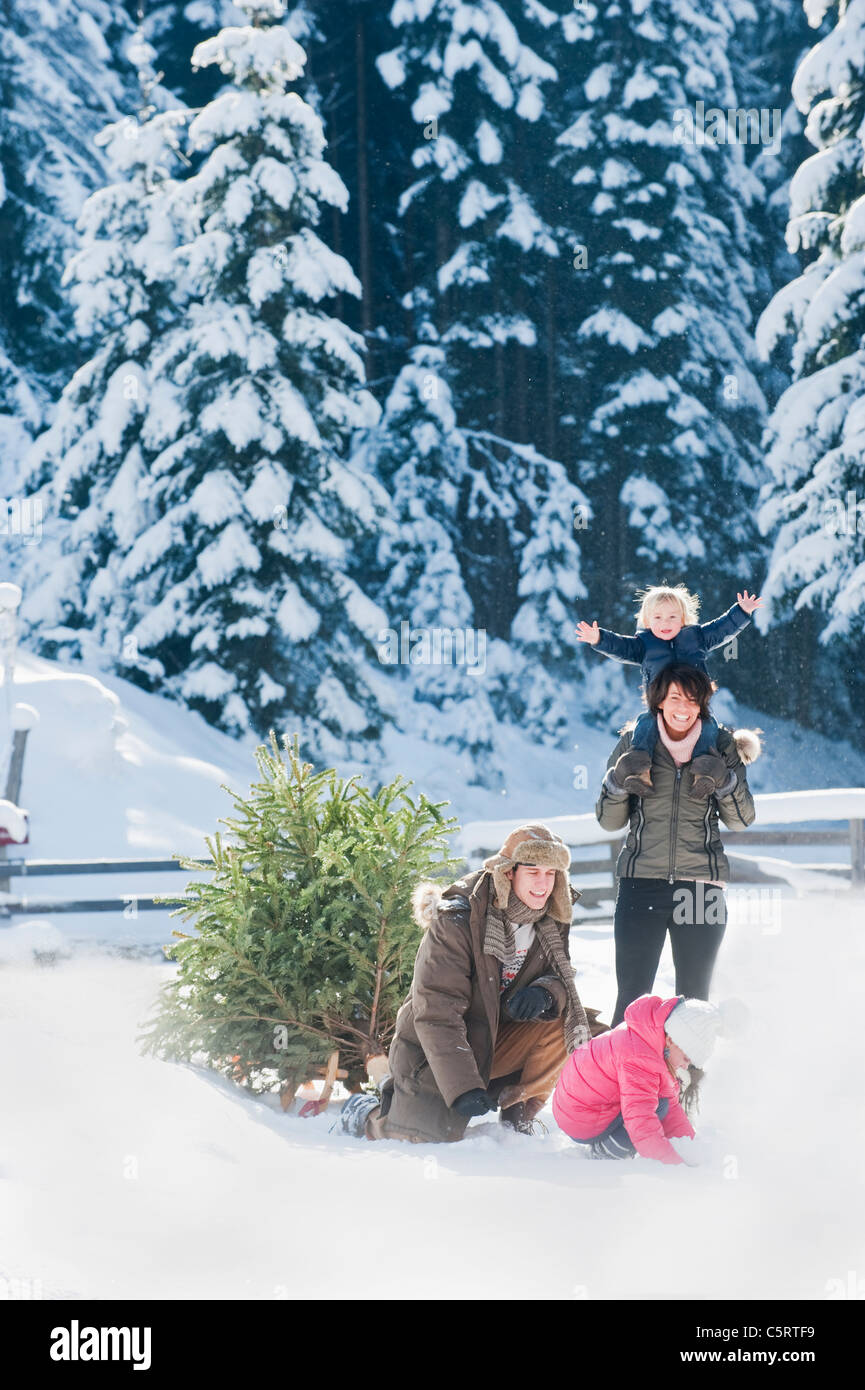 Österreich, Salzburger Land, Flachau, Blick auf Familie mit Weihnachtsbaum und Schlitten im Schnee spielen Stockfoto