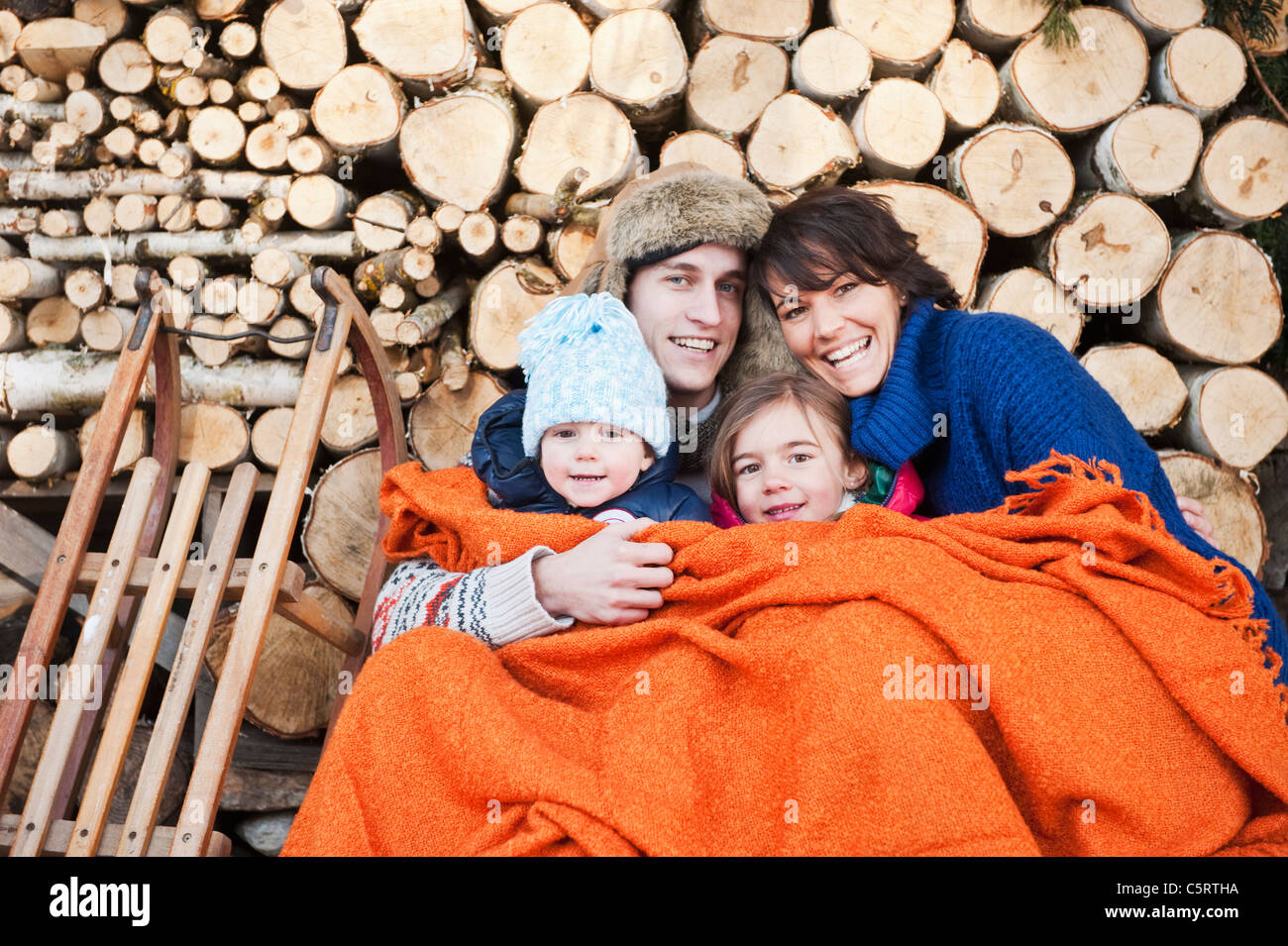 Österreich, Salzburger Land, Flachau, Familie unter Wolldecke sitzen vor Brennhölzer Stockfoto