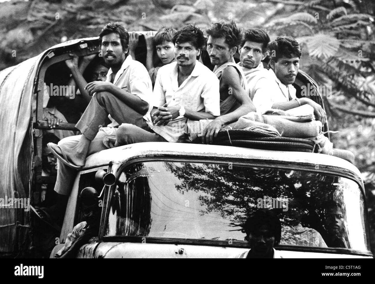 Männer und Kinder, die auf dem Dach eines LKW durch das Land in der Armen Region von Orissa in Indien 1992 Stockfoto