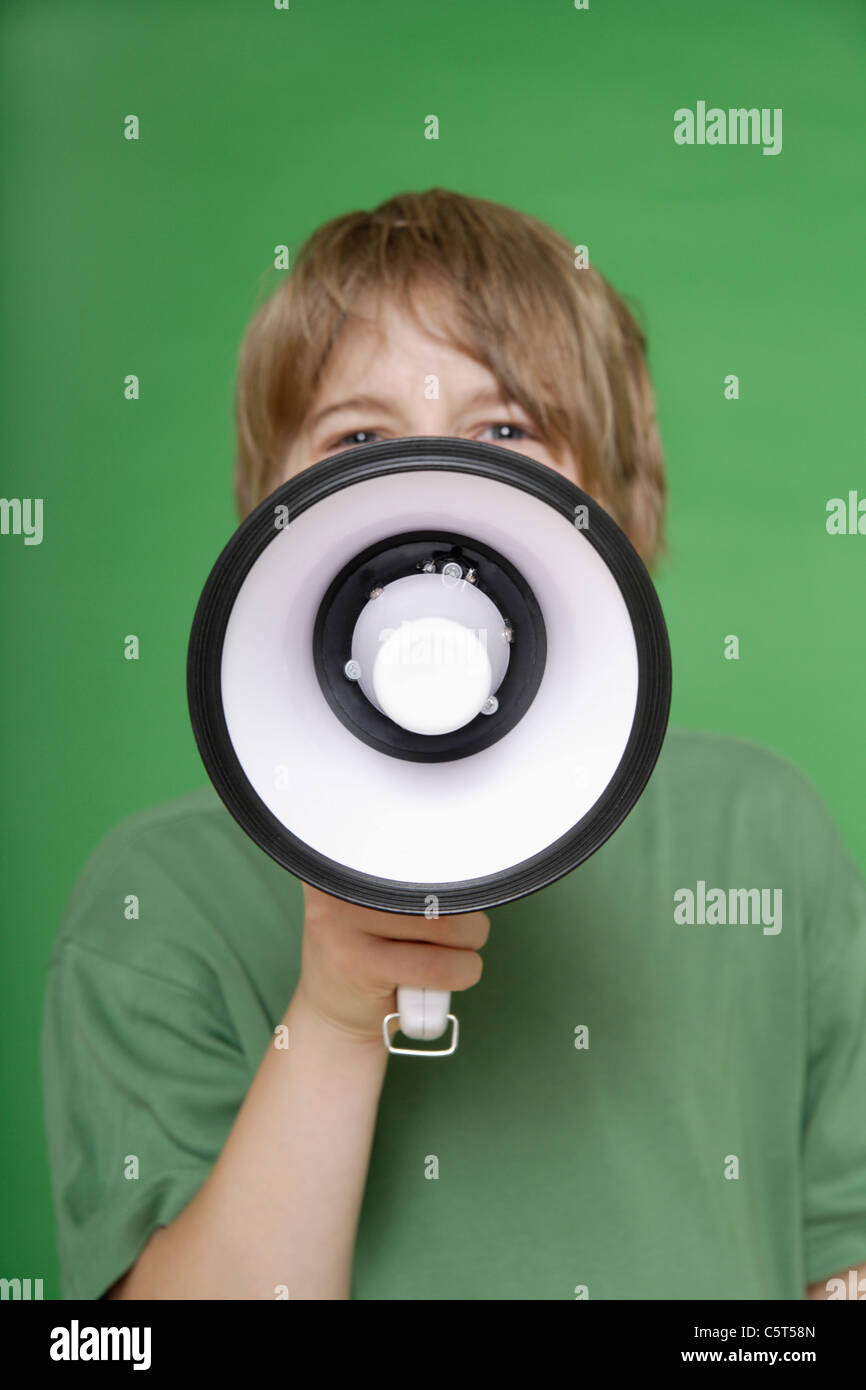 Nahaufnahme eines Jungen schreien im Megaphon vor grünem Hintergrund Stockfoto