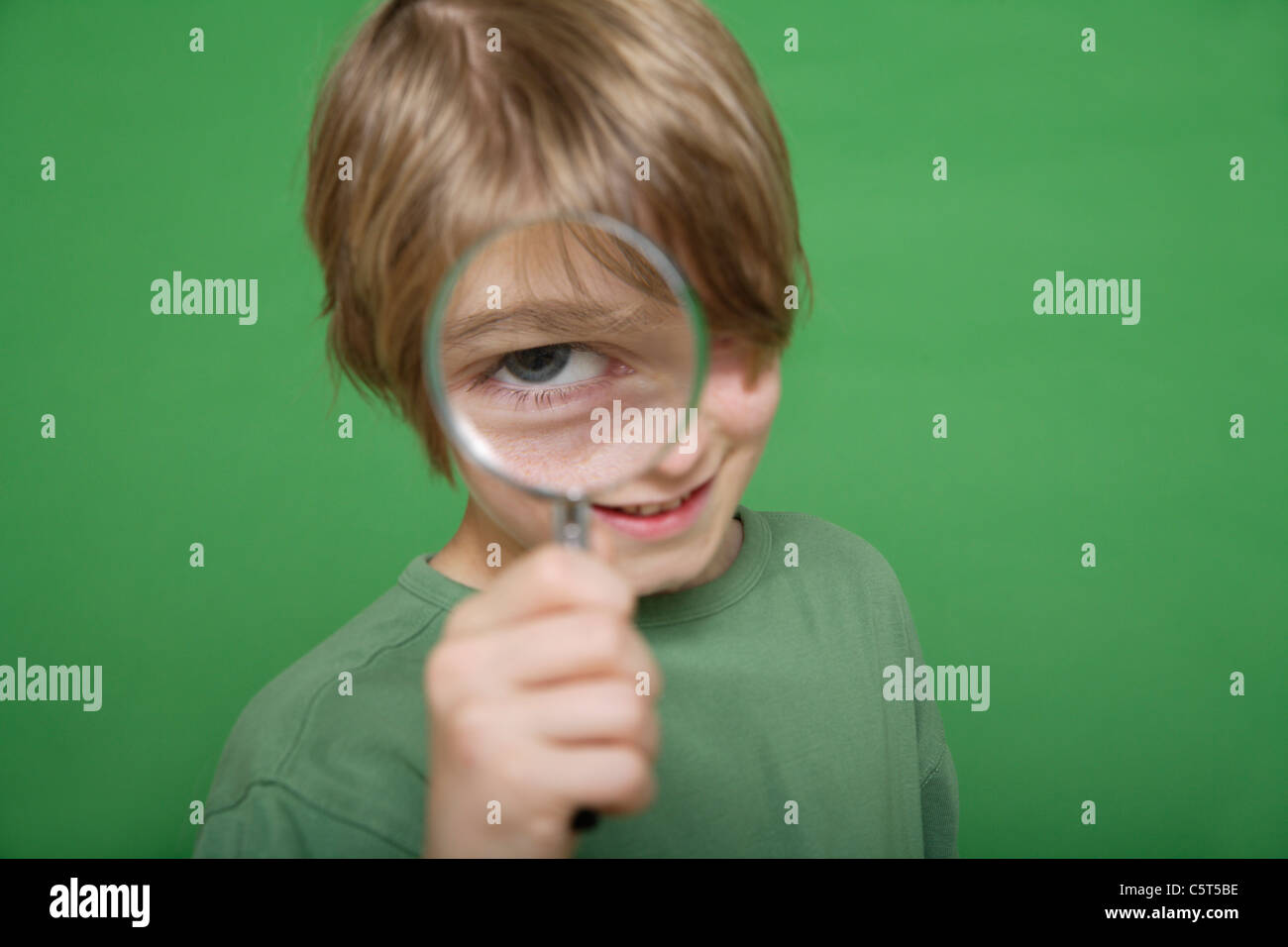 Nahaufnahme eines jungen Blick durch die Lupe vor grünem Hintergrund Stockfoto