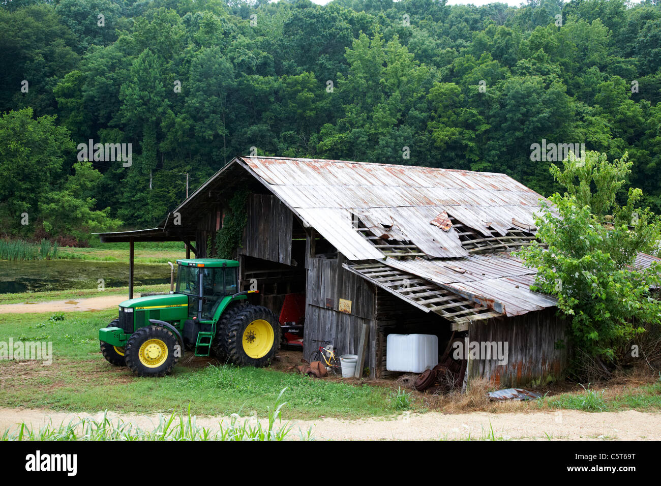 Traktor in alten abgenutzten angeschlagenen traditionellen Bauernhof Gebäude in Lichtung im Wald Hurrikan Mühlen Tennessee usa Stockfoto