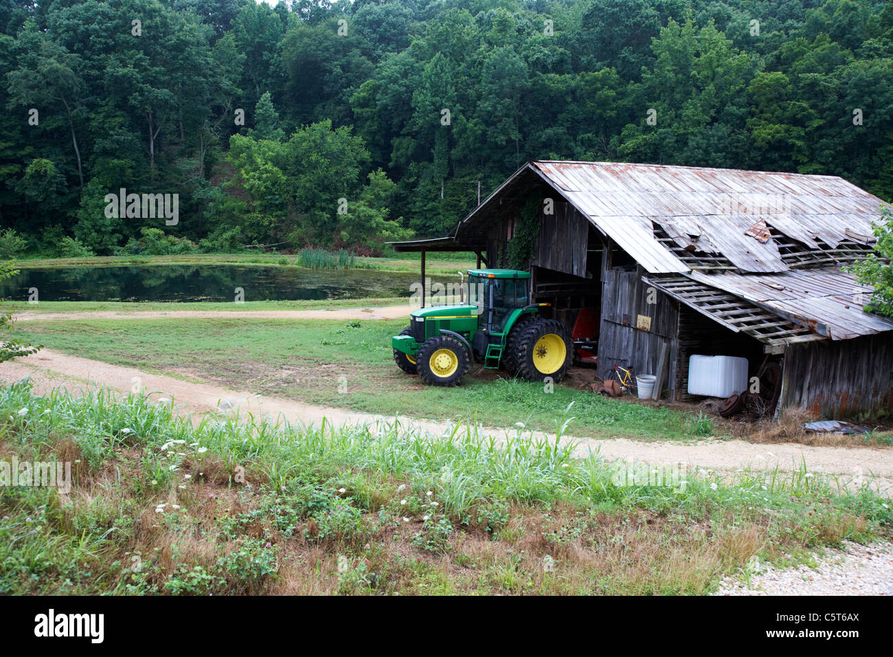Traktor in alten abgenutzten angeschlagenen traditionellen Bauernhof Gebäude in Lichtung im Wald Hurrikan Mühlen Tennessee usa Stockfoto